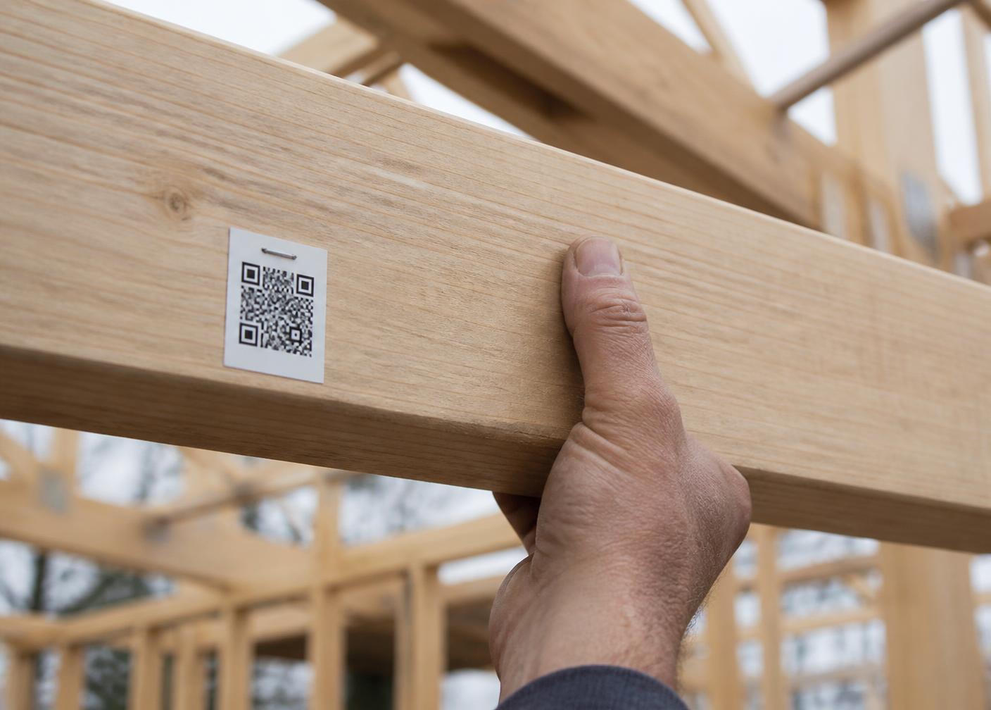Timber beam with a QR label being handled on a construction site